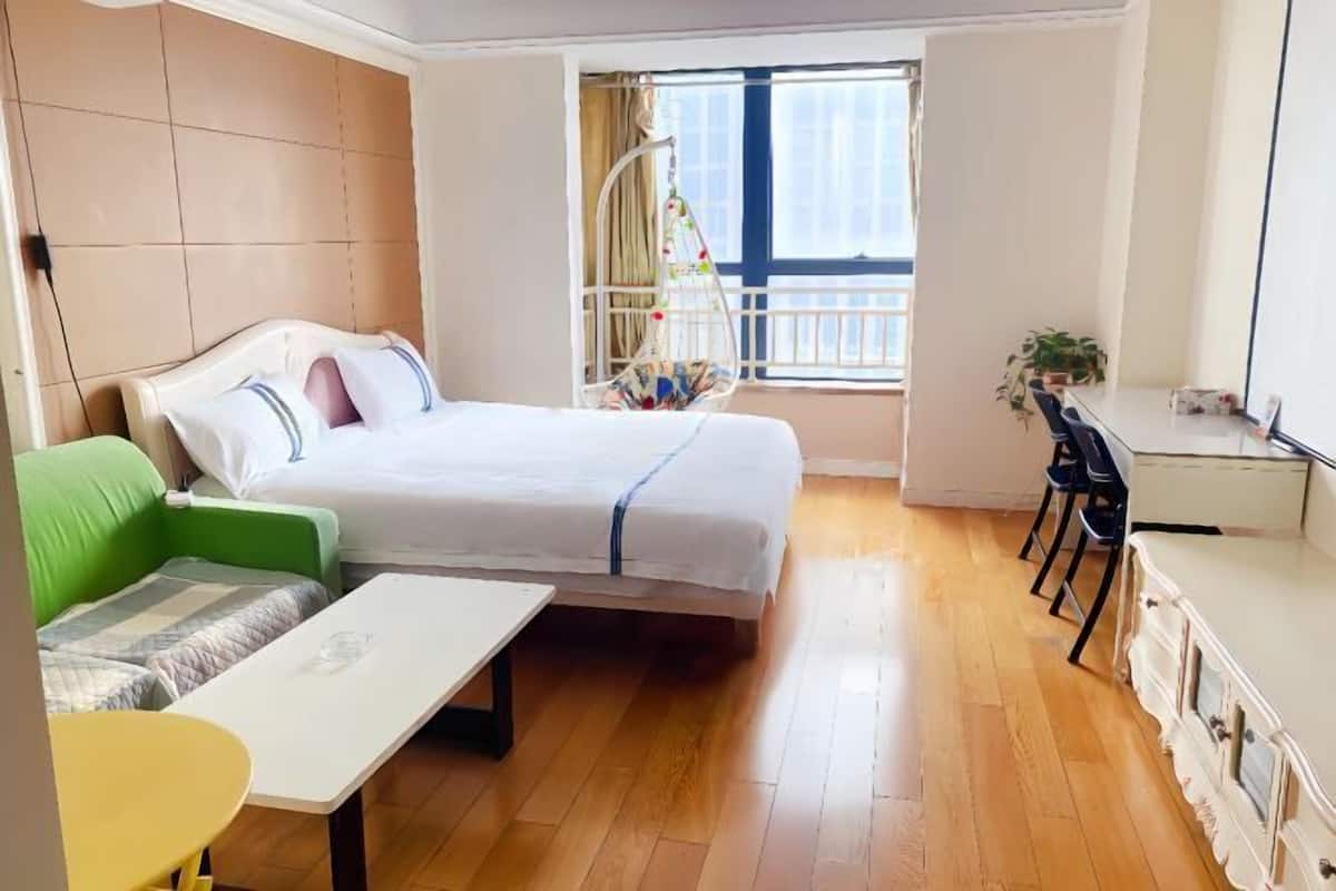 Ein Schlafzimmer mit einem Bett, einem grünen Sofa, einem kleinen Tisch und einem Schreibtisch mit Stühlen.