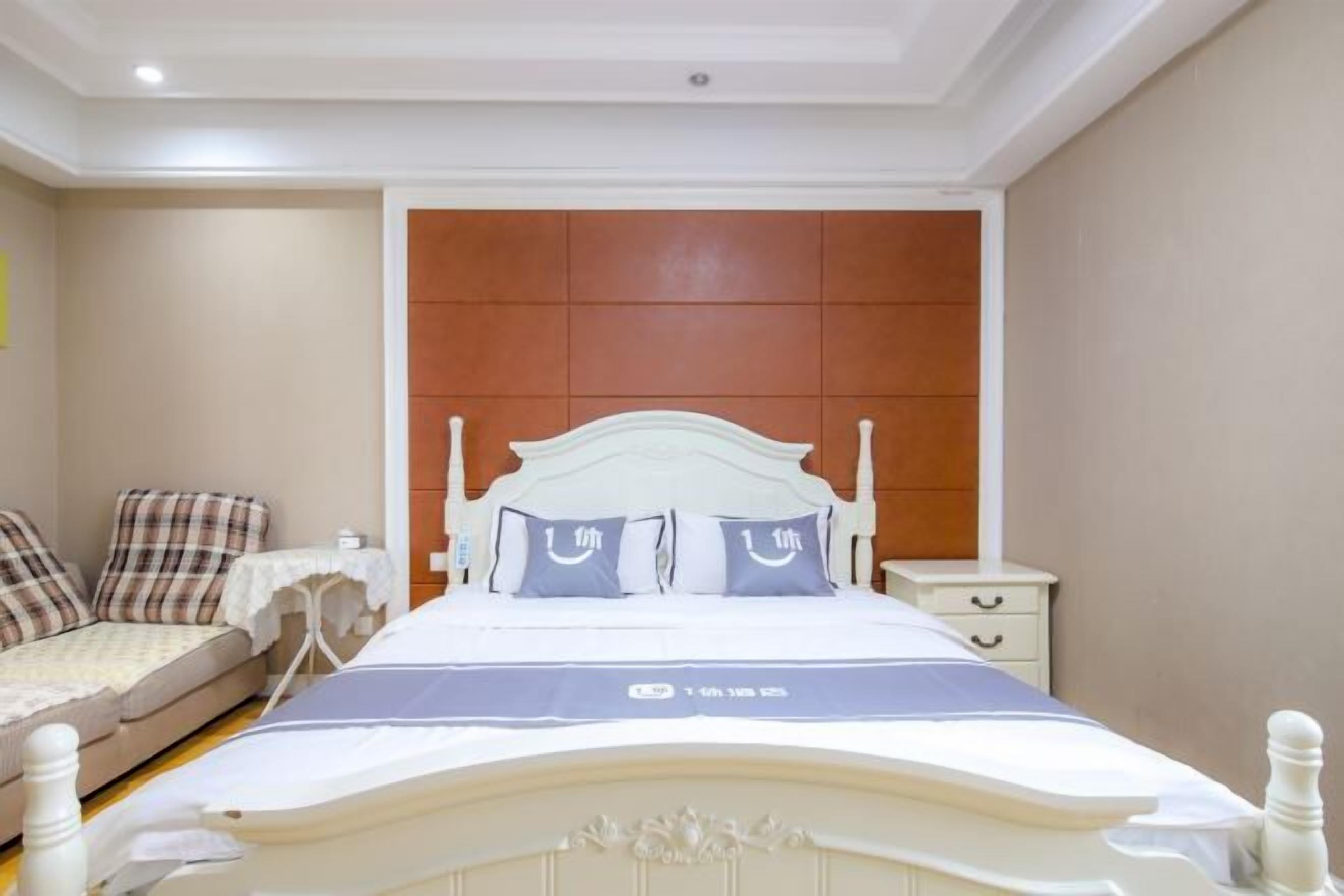 A bedroom with a bed, a bedside table, a nightstand, and a sofa.