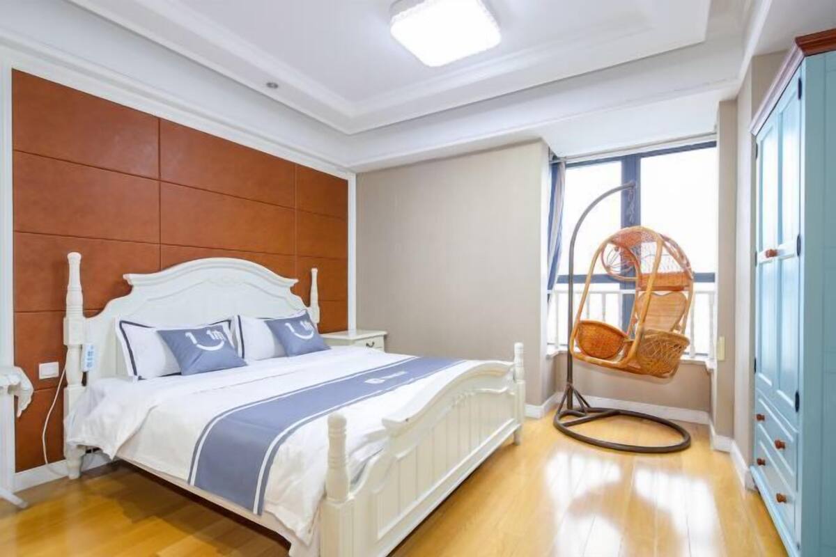 Ein Schlafzimmer mit einem Bett, einem Hängestuhl, einem Kleiderschrank und einem Fenster.