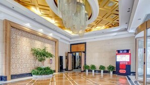 Un hall espacioso con piso de mármol pulido, un gran candelabro y un moderno mostrador de recepción.