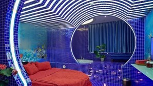 Een ronde kamer met een bed, een spiegel en een vloer van blauwe tegels.