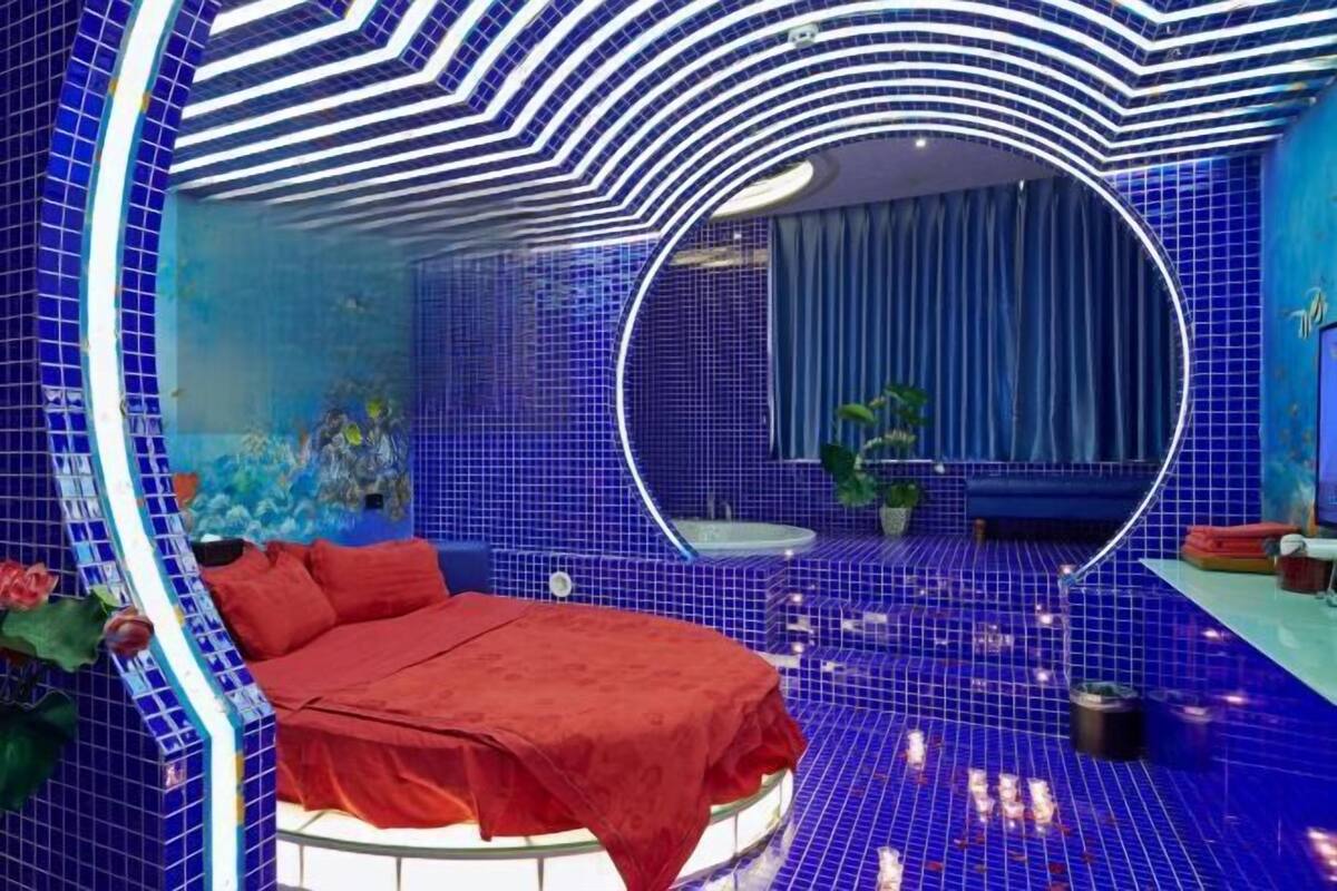 Habitación circular con cama, espejo y suelo de baldosas azules.