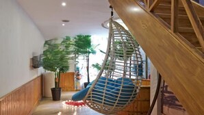 Een trap met een hangstoel, kamerplanten en een houten vloer.