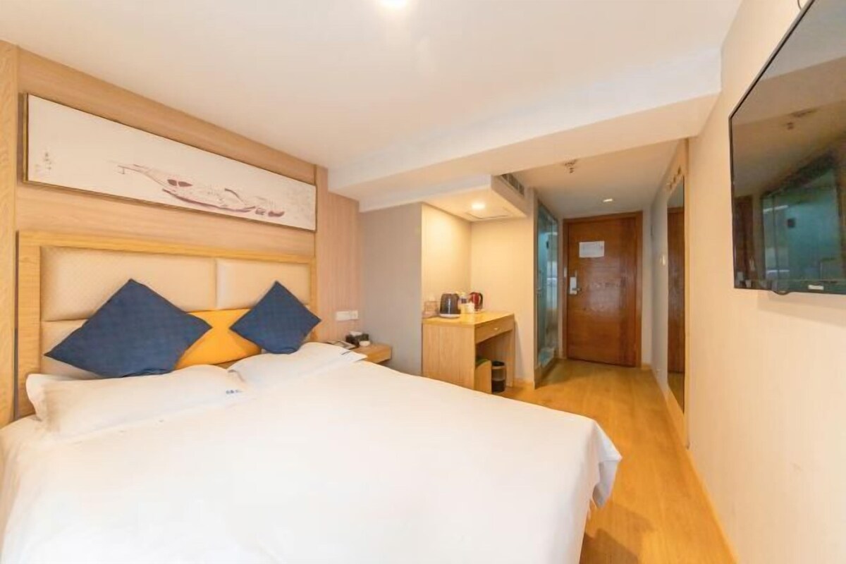 Una habitación de hotel con una cama grande, cabecera de madera, escritorio y espejo.