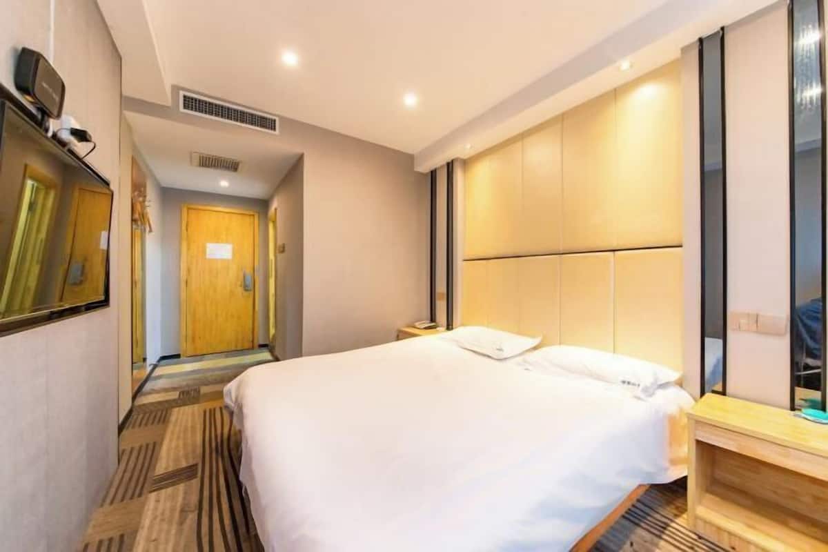 Una habitación de hotel con una cama grande, un cabecero de madera, una mesita de noche y un espejo.