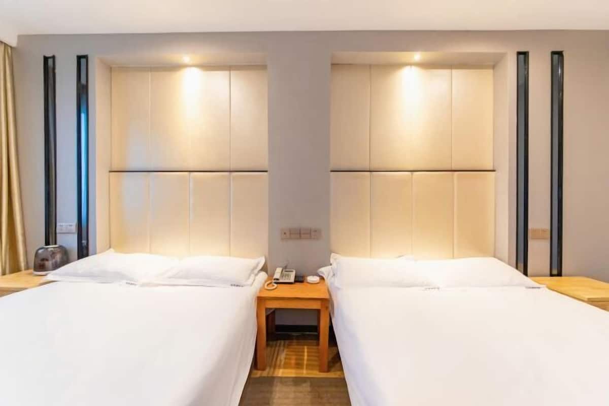 Una habitación de hotel con dos camas, una mesita pequeña con un teléfono y una mesita de noche.