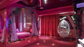 A room with a canopy bed, red curtains, a neon sign, and a decorative egg chair.