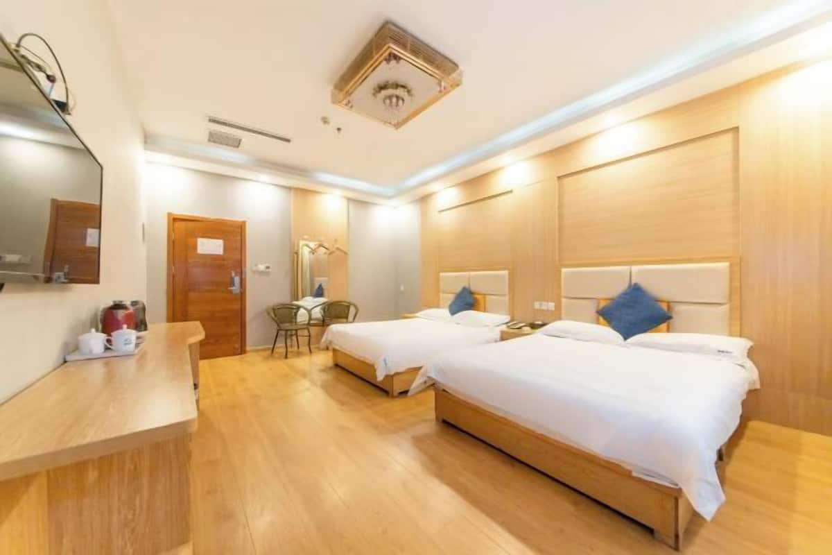 Habitación de hotel con dos camas, un escritorio de madera, una silla y un espejo.