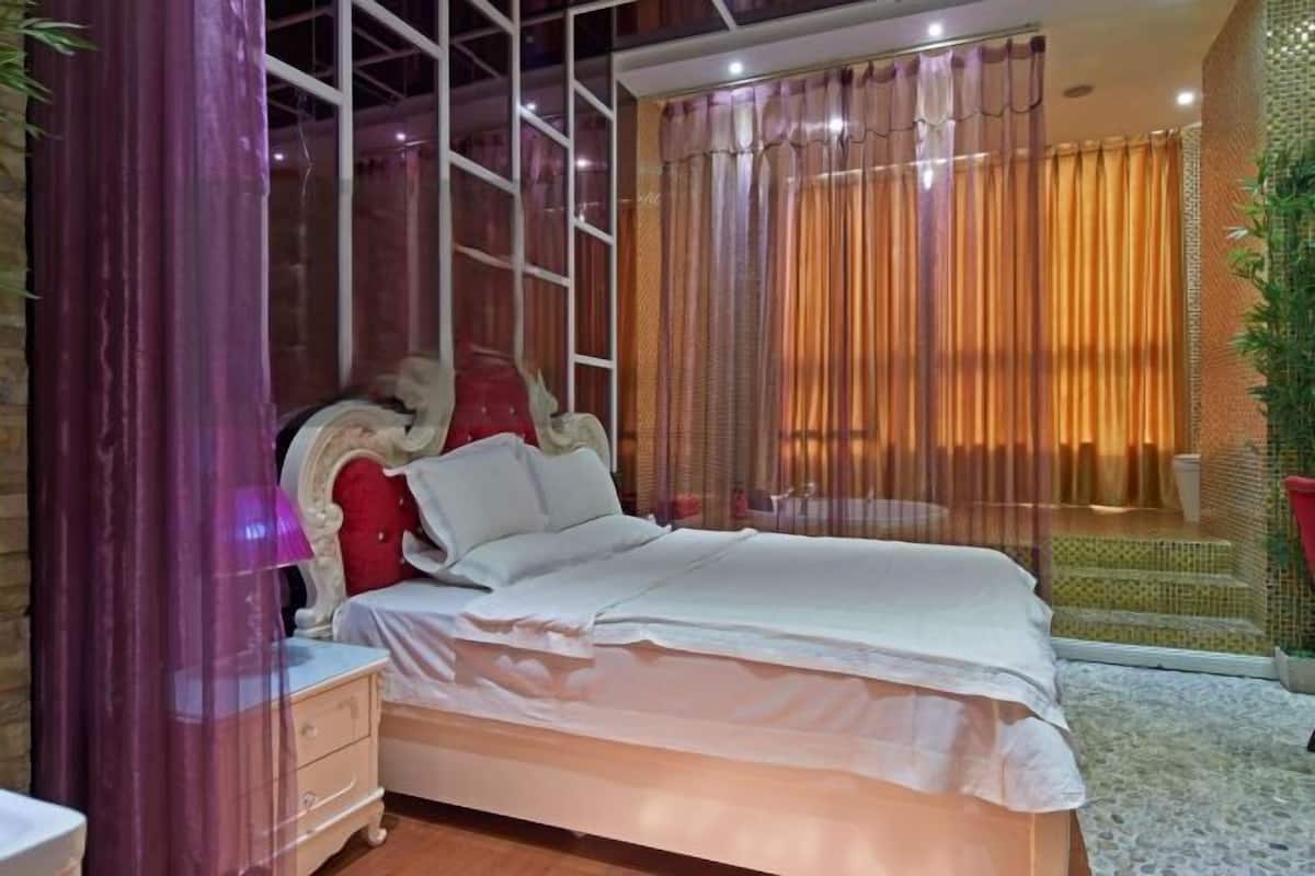 Un dormitorio con cama, una mesita de noche, una ventana con cortinas y vistas a un jardín.