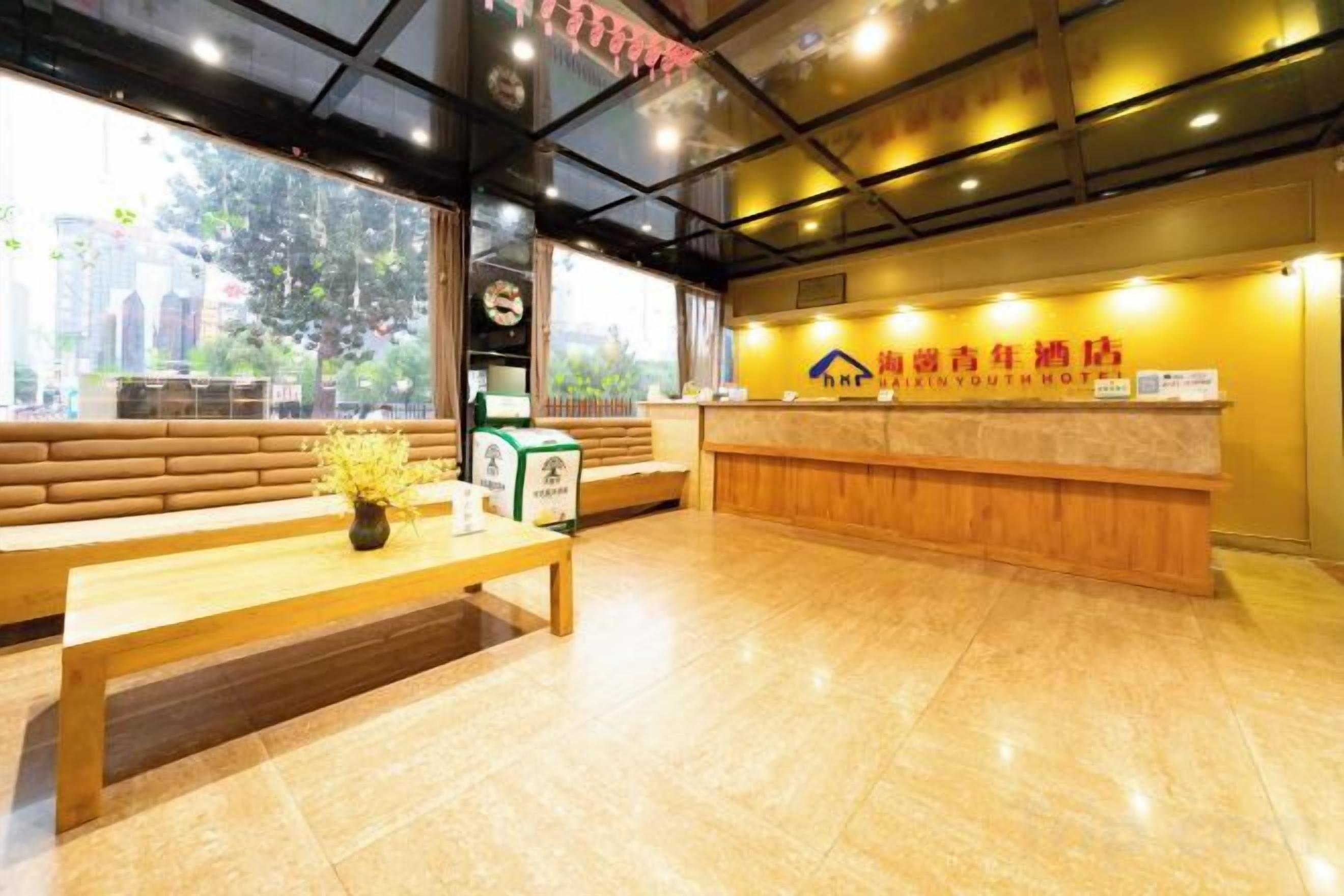 A reception area with a wooden bench, a reception desk, and a sign indicating a youth hostel.