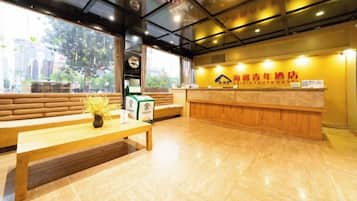 A reception area with a wooden bench, a reception desk, and a sign indicating a youth hostel.