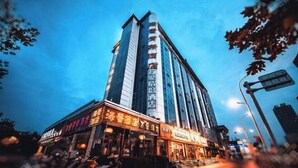 Een hoog hotel met meerdere verdiepingen, met verlichte borden en een opvallende ingang.