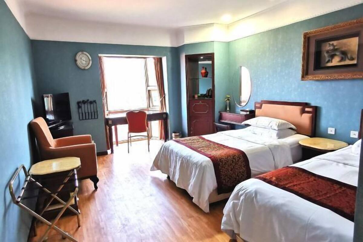 A hotel room with two beds, a desk, a chair, and a small table.