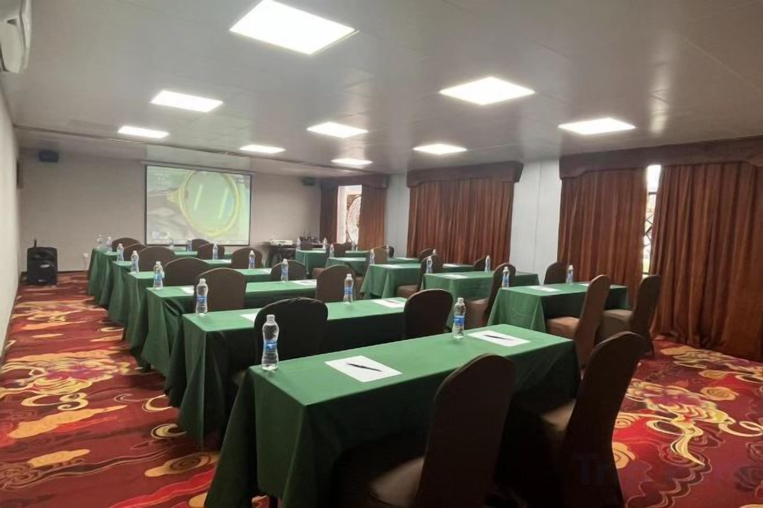 A conference room with tables, chairs, and a projector screen.