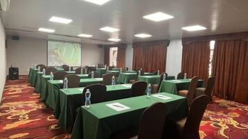 A conference room with tables, chairs, and a projector screen.
