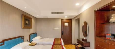 A hotel room with two beds, a wooden wardrobe, a desk, and a mirror.