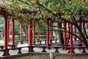 A traditional Japanese torii gate structure with a curved roof, surrounded by a stone pathway and benches. - Lakeside Garden Wudelou Hotel (Wuhan)