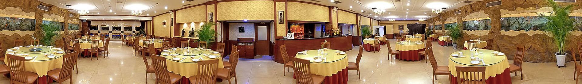 A hotel dining area with round tables, chairs, and a bar.