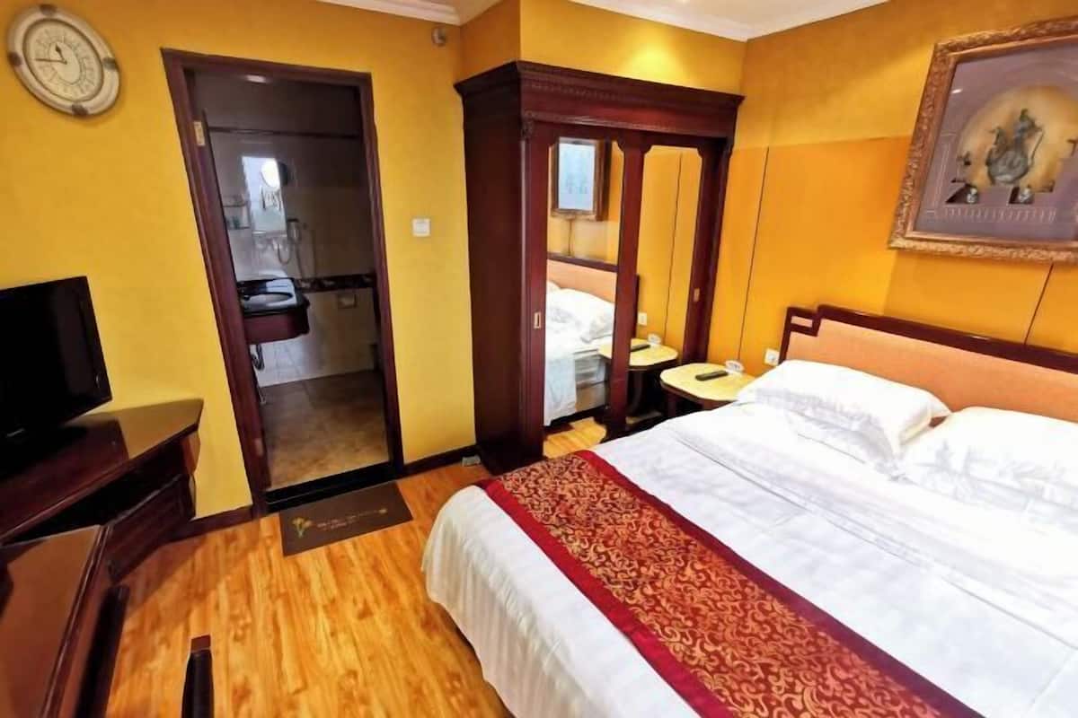 A hotel room with a bed, a television, a wardrobe, and a bathroom visible through an open door.
