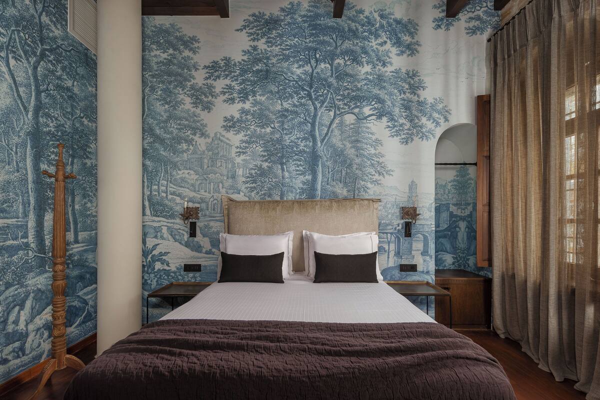 A bedroom with a large bed, a headboard, two bedside tables, and a nightstand.