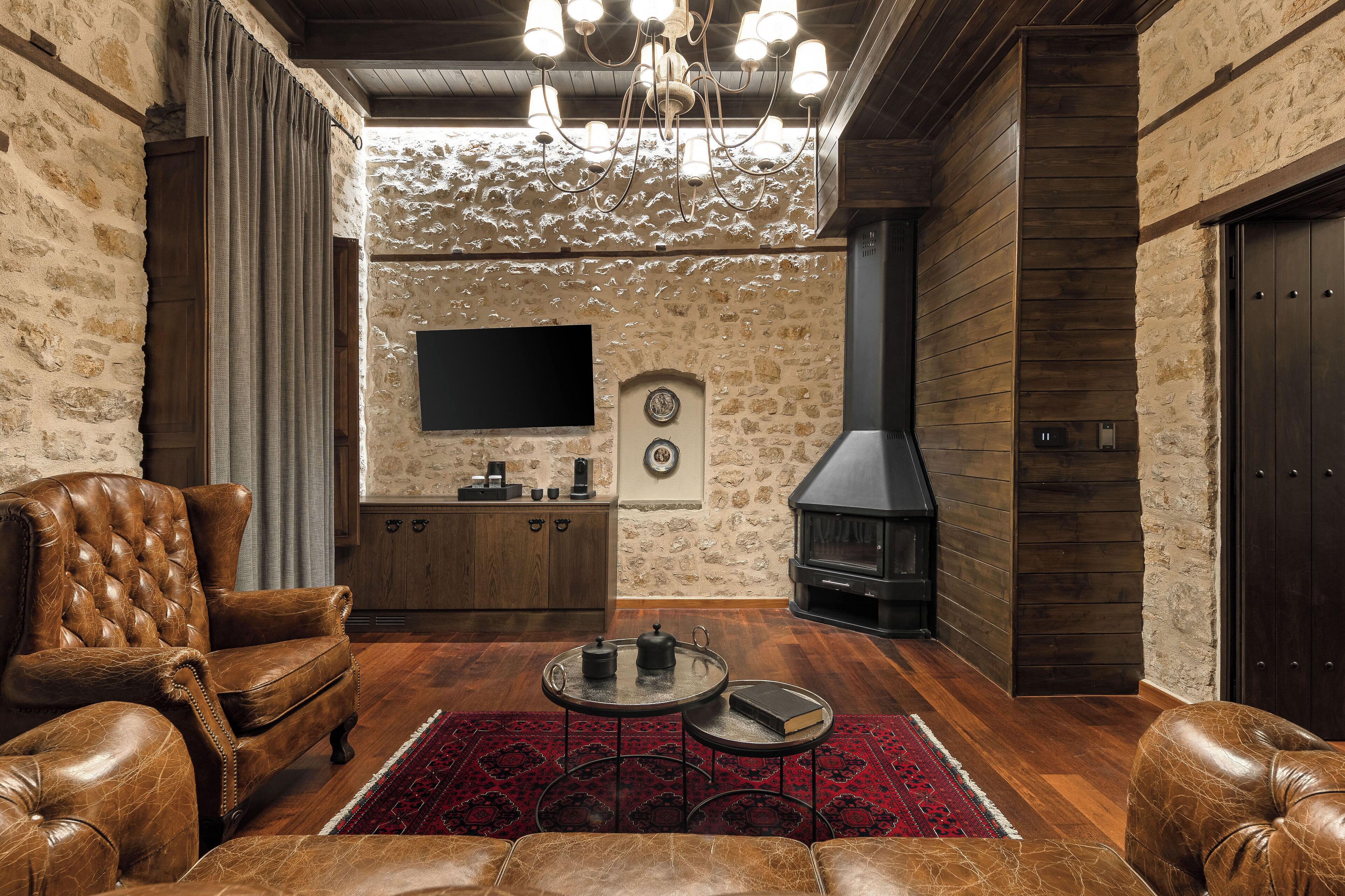 Una sala de estar acogedora con mobiliario de cuero, chimenea y pared de piedra.