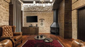 Una sala de estar acogedora con mobiliario de cuero, chimenea y pared de piedra.