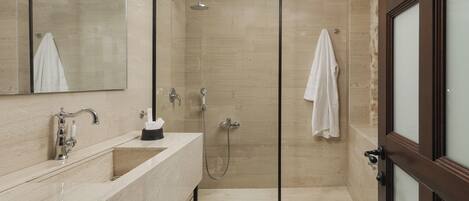 A modern bathroom with a glass-enclosed shower, a marble sink, and a white toilet.