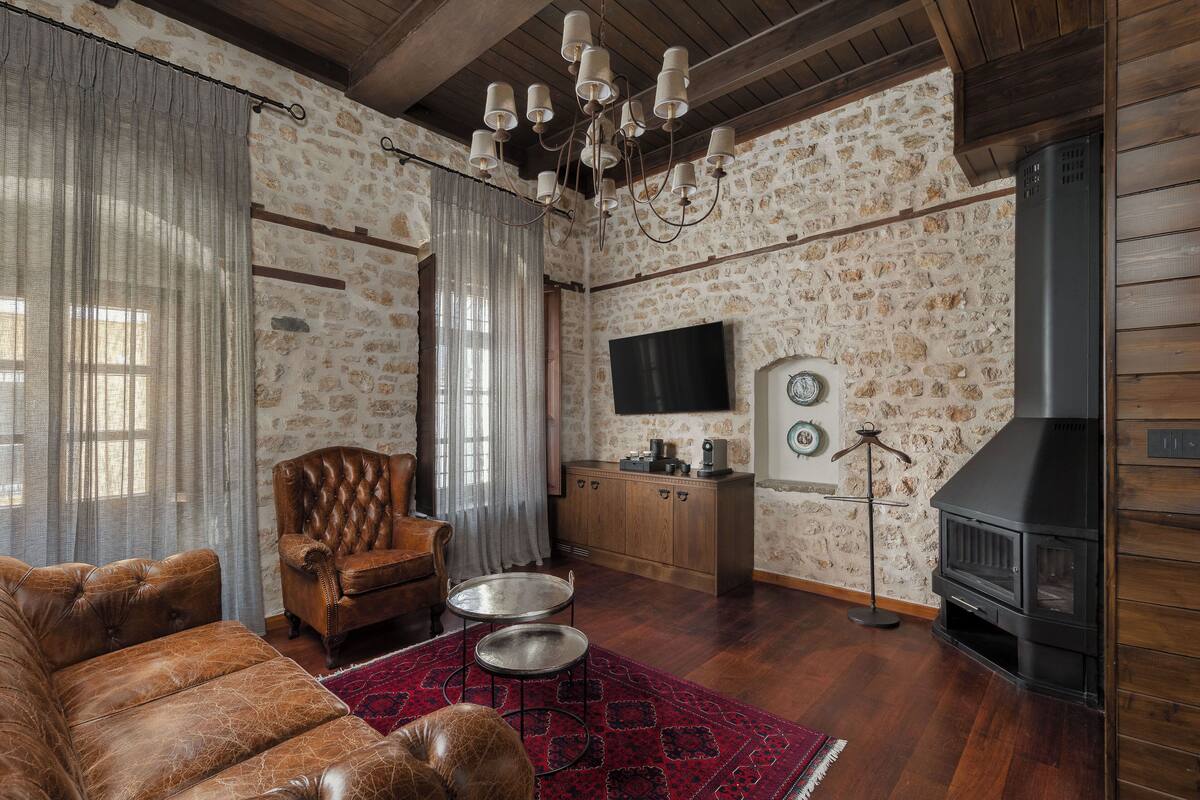 A cozy living room with a leather sofa, a wooden cabinet, a television, and a fireplace.