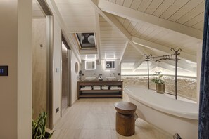 A modern bathroom with a skylight, a bathtub, and a vanity with two sinks.