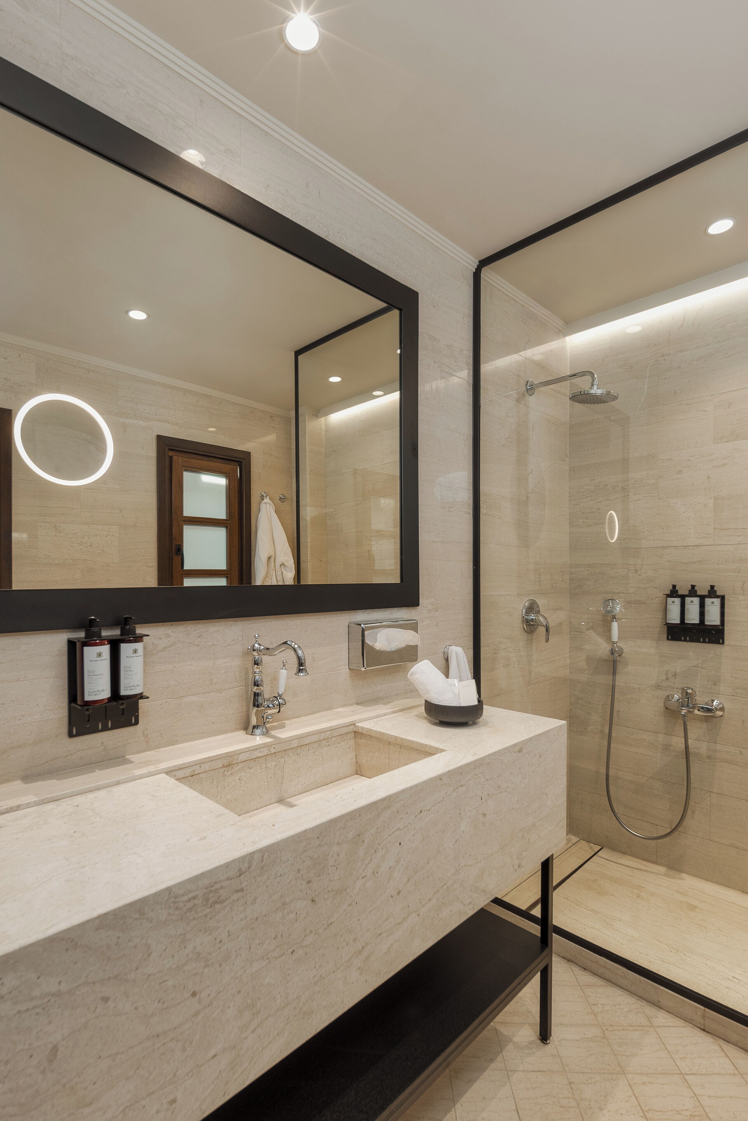 Un baño moderno con un espejo grande, lavamanos dobles, ducha y toallero.