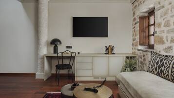 A modern living room with a sofa, a coffee table, a desk with a chair, and a television mounted on the wall.