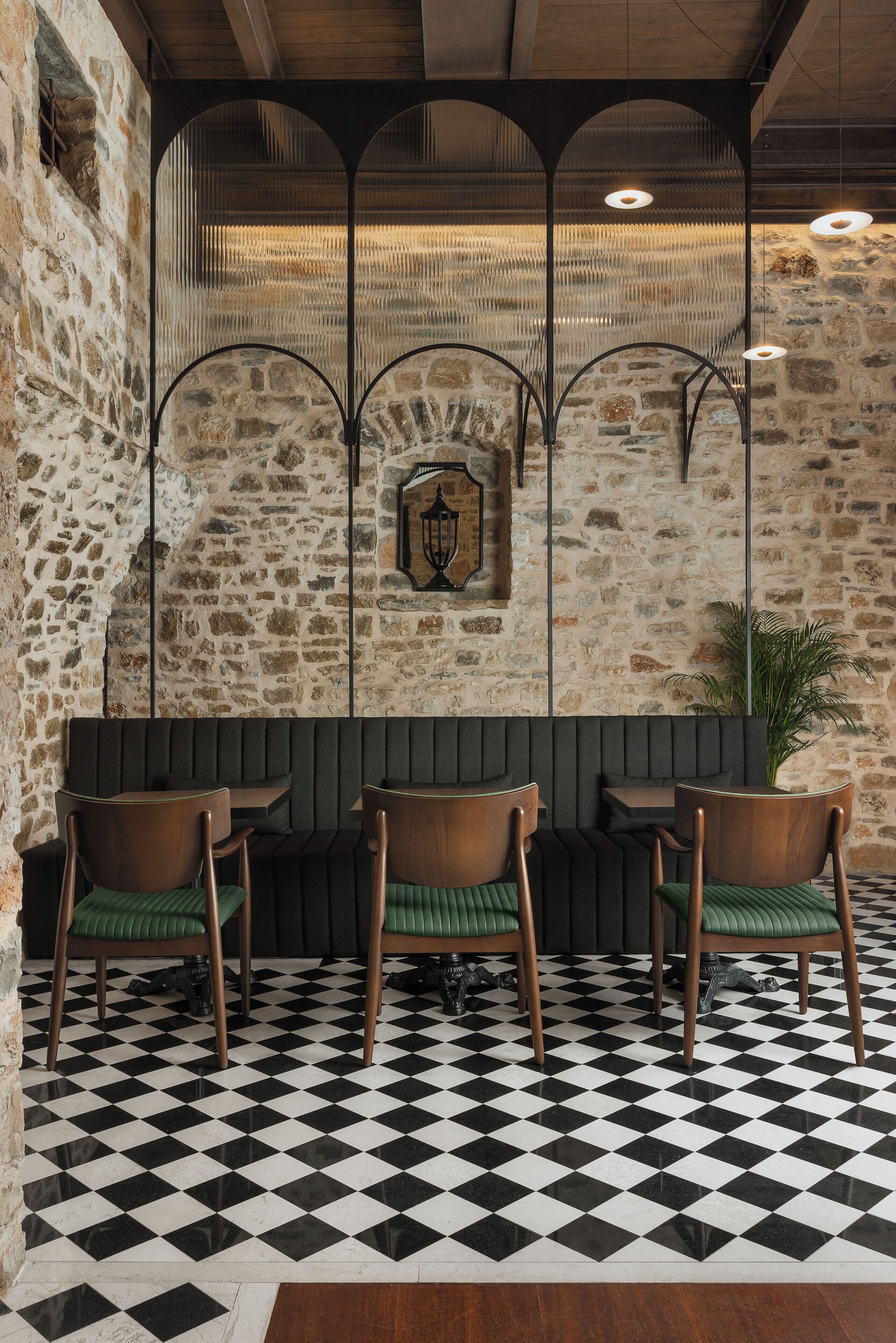 A checkered floor, a stone wall, and a bench with chairs.