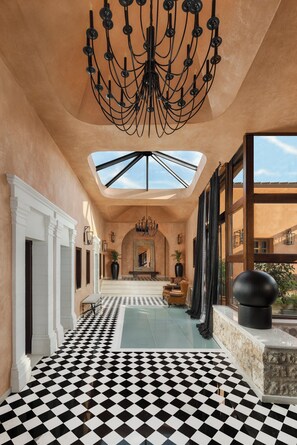 A hallway with a black and white checkered floor, a chandelier, and a skylight.