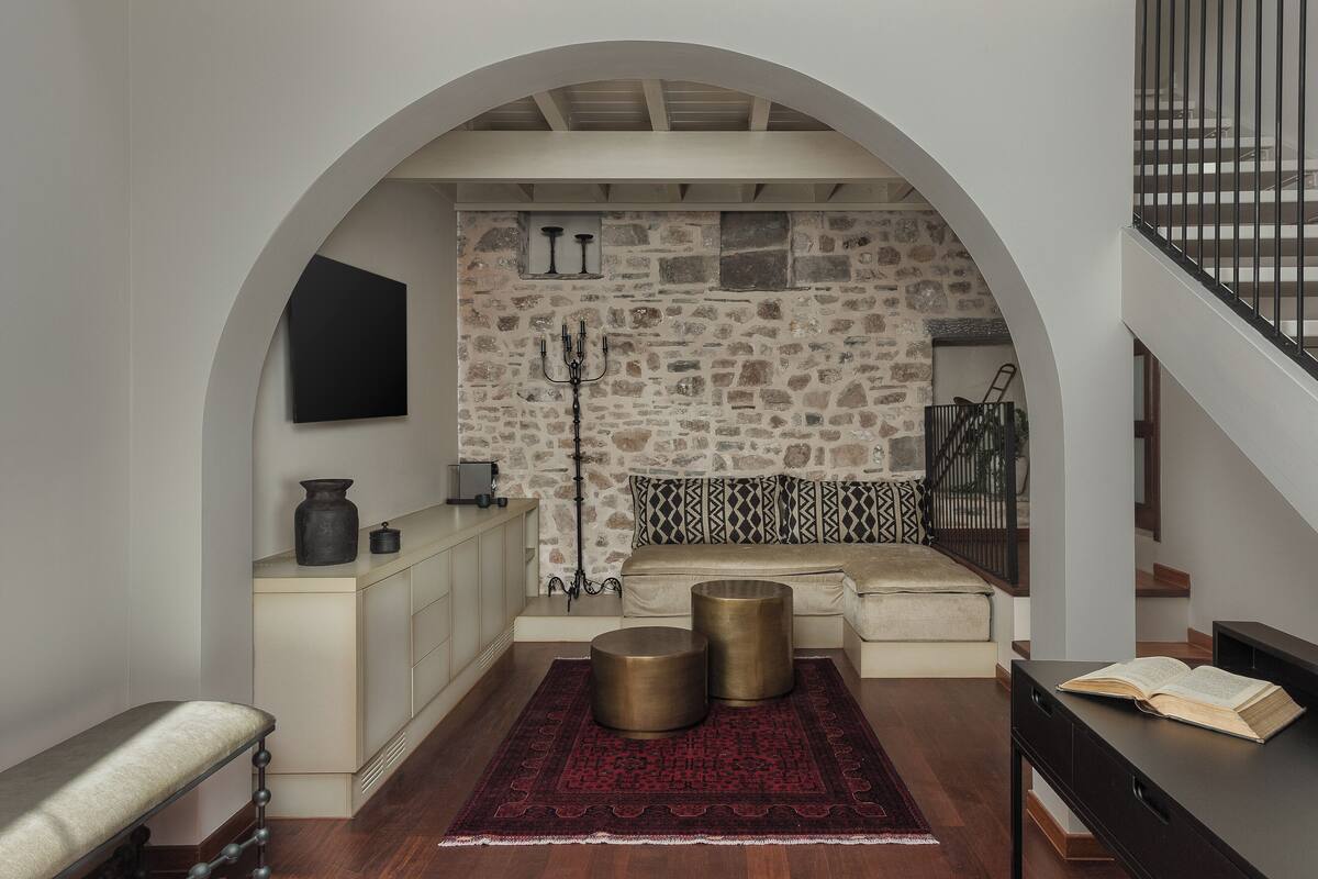 A modern interior with a stone wall, a bench, a sofa, and a staircase.