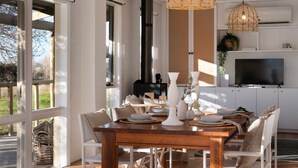 A dining area with a wooden table, white chairs, and a modern kitchen in the background. - The Cottage at Lake Werona (Werona)