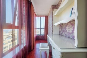 Ein Zimmer mit Blick durch ein Fenster, eine weiße Kommode und ein kleiner Tisch.