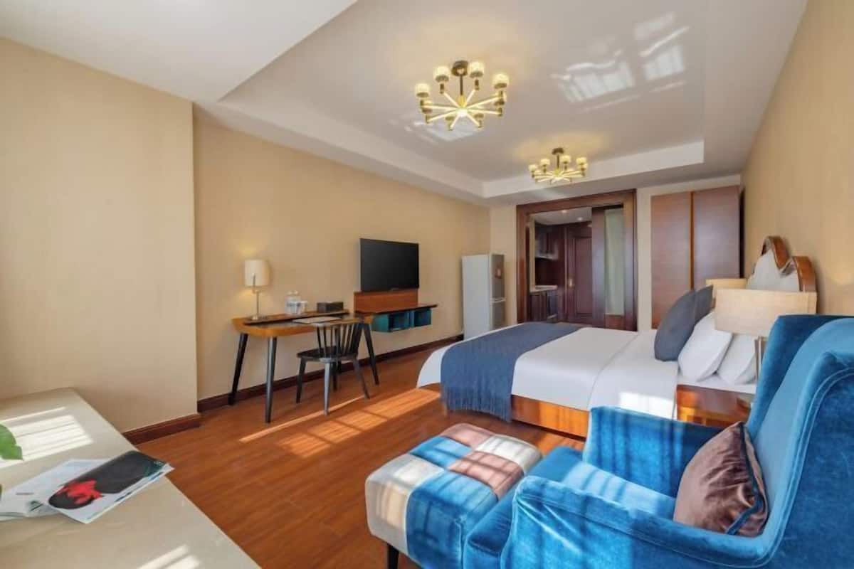 Ein Hotelzimmer mit einem Bett, einem Schreibtisch, einem Sessel, einem Fernseher und einem Sofa.