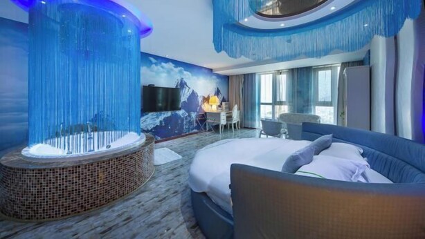 A modern hotel room with a large bed, a seating area, and a wall-mounted TV. - Ice Dream Fantasy Hotel (Hengdian Film and Television City Pedestrian Street) (Dongyang)