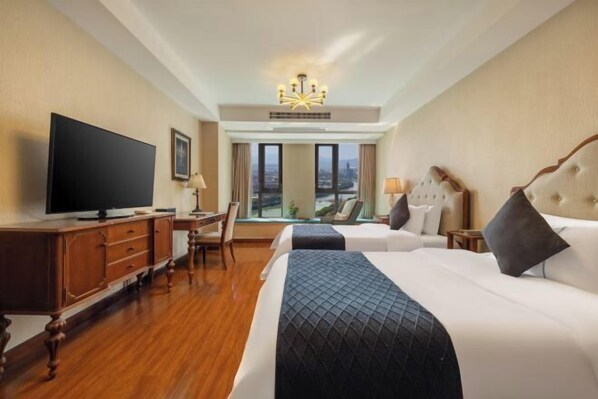 Une chambre d’hôtel avec un grand lit, une télévision, un bureau et une vue sur la ville.