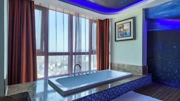 Un baño moderno con una bañera grande, vistas de la ciudad a través de amplios ventanales y un techo con diseño de estrellas.