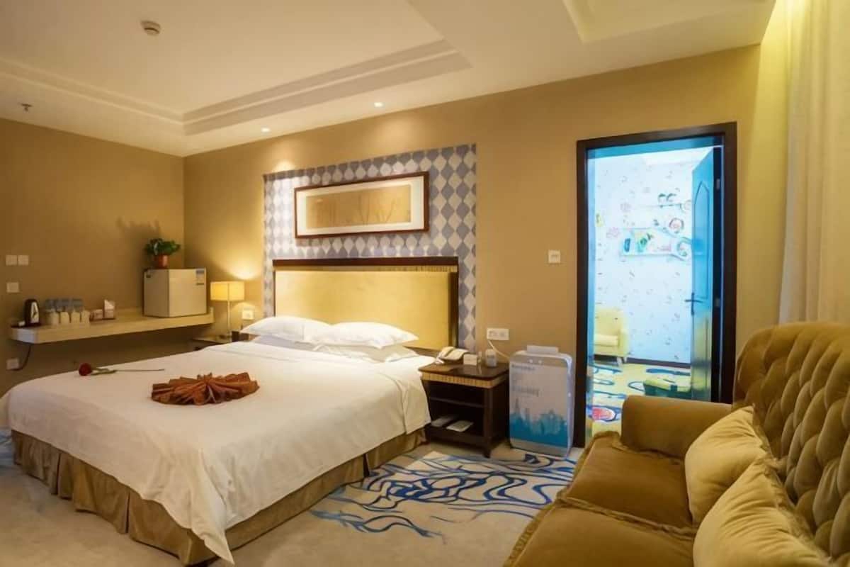 Una habitación de hotel con una cama, una mesita de noche, una lámpara, un televisor y un sofá.