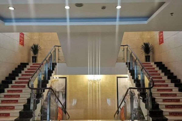 A hotel lobby with a central staircase, a chandelier, and potted plants. - Huixian Shangquan Yipin Hotel (Huixian)