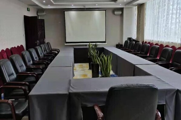 A conference room with a long table, black chairs, a projector screen, and a potted plant. - Huixian Shangquan Yipin Hotel (Huixian)