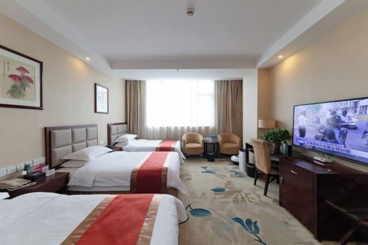 Habitación de hotel con dos camas, un televisor, un escritorio y una silla.