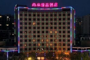 A hotel with a grid of windows, neon signage, and a flat roof. - Huixian Shangquan Yipin Hotel (Huixian)