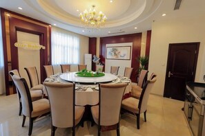 Een eetkamer met een ronde tafel, stoelen, een kroonluchter en een bordje met de tekst 'Welkom Onze Baby'.
