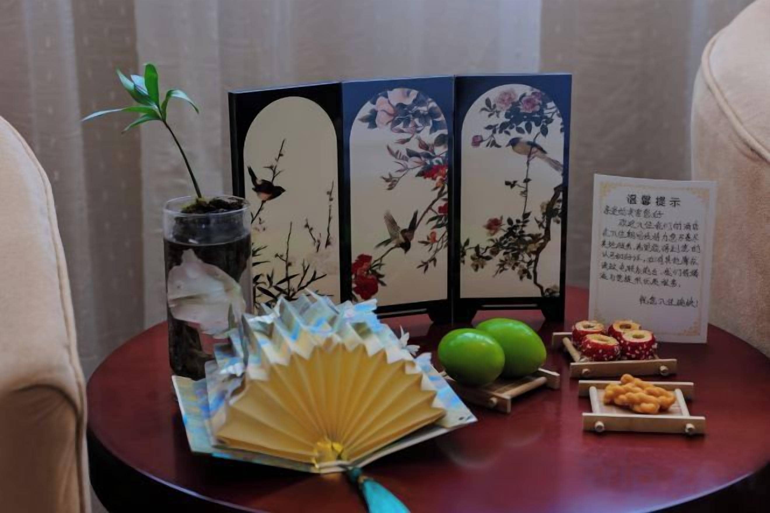 Une pièce de style japonais traditionnel, avec un sol recouvert de tatamis, un paravent en papier de riz (shoji), un bonsaï, un éventail et une petite table sur laquelle sont disposés des en-cas.