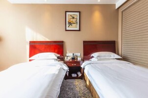 Una habitación de hotel con dos camas, una mesita de noche, un cuadro enmarcado en la pared y una ventana con persianas.