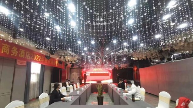 Une salle de conférence avec une longue table, des chaises blanches et un fond rouge.