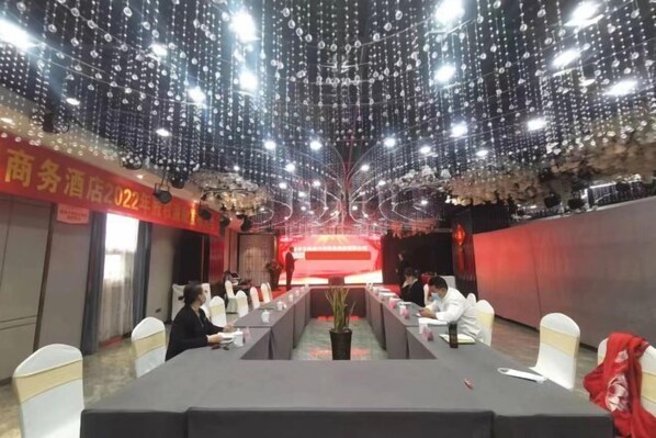 A conference room with a long table, white chairs, and a red backdrop. - Huixian Shangquan Yipin Hotel (Huixian)